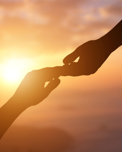 Silhouette of two hands reaching towards each other against a sunset background, symbolizing connection and love.