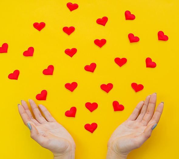 Hearts in hands on yellow background