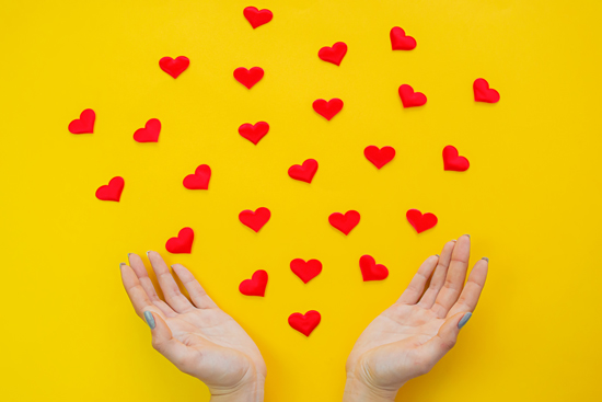 Hearts in hands on yellow background