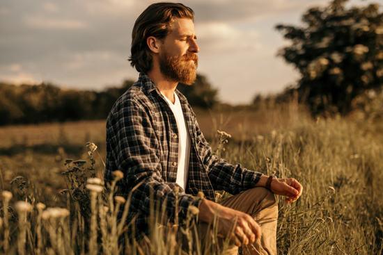 Man meditating in open field at sunset